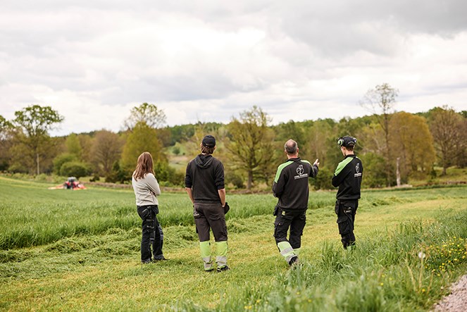Fyra lantbrukare står på en åker och samtalar. 