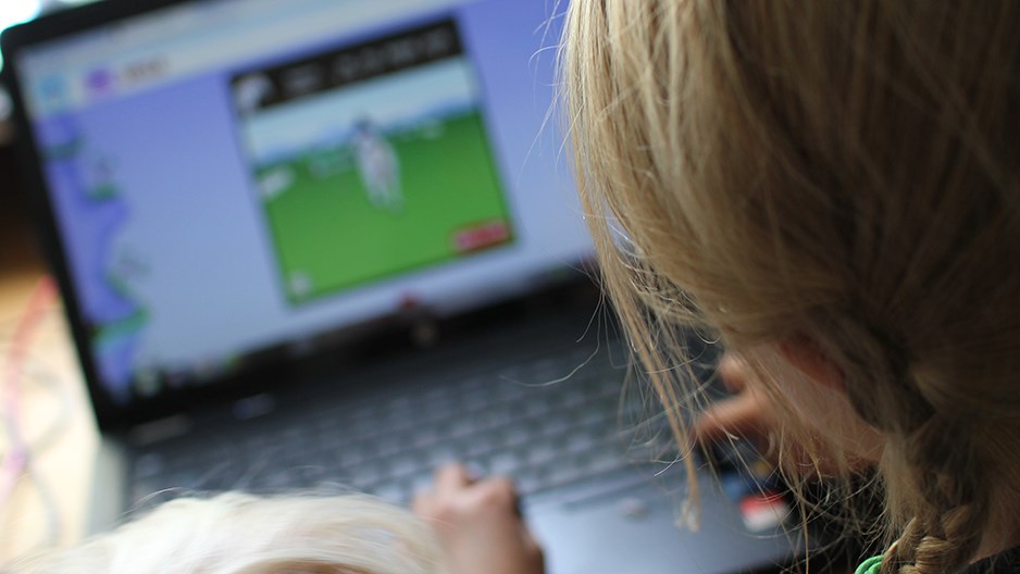 Barn som sitter vid en bärbar dator och arbetar med tangentbordet. På skärmen syns en bild och text.